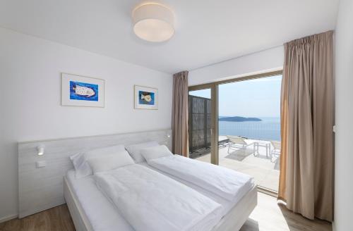 a white bedroom with a bed and a large window at Zlatni Zalaz,Apartments,Supetarska Draga in Supetarska Draga