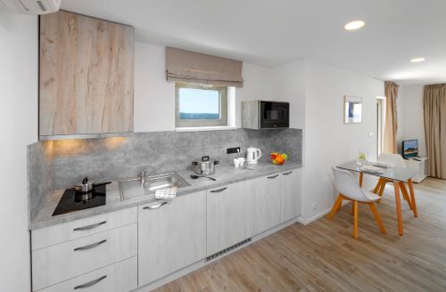 a kitchen with white cabinets and a sink and a table at Zlatni Zalaz,Apartments,Supetarska Draga in Supetarska Draga