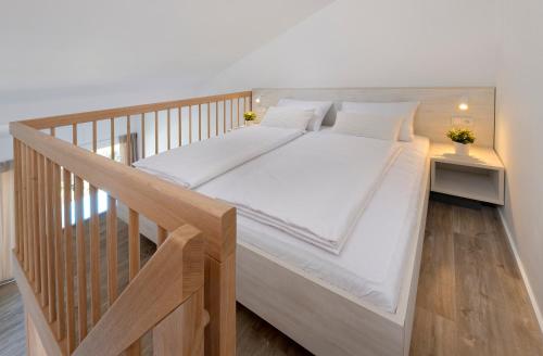 a wooden bed with white sheets and pillows at Zlatni Zalaz,Apartments,Supetarska Draga in Supetarska Draga