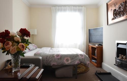 a bedroom with a bed and a vase of flowers on a table at Dale Street Apartments Suite in Leamington Spa