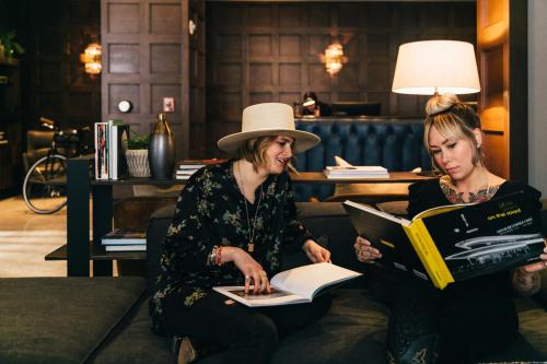 two women sitting on a couch reading books at Dossier in Portland