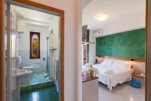 a bedroom with a bed and a bathroom with a sink at Hotel Orsa Maggiore in Vulcano