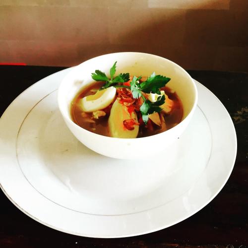 a bowl of soup on a plate on a table at Villa Puspa in Tanah Lot