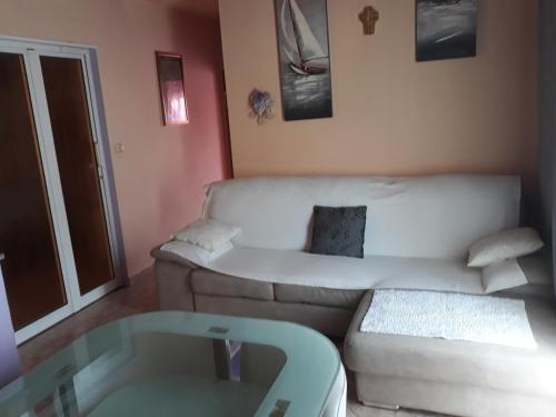 a living room with a white couch and a glass table at Apartmani Premijer-Rab in Supetarska Draga