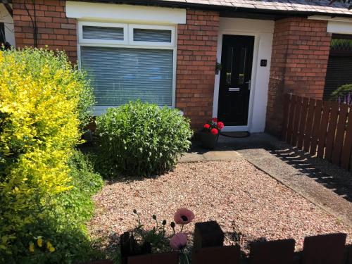 a house with a door and a yard with flowers at Belfast Holiday Home in Belfast