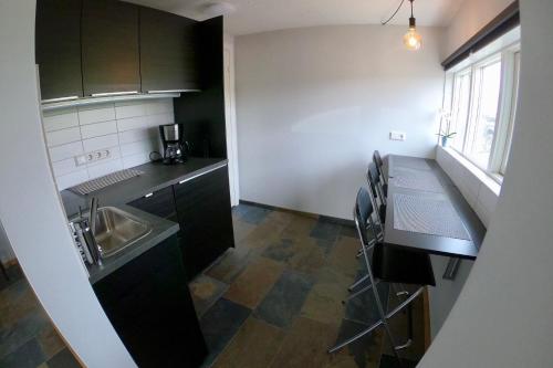 a small kitchen with black cabinets and a sink at Hamrar in Einarsstaðir