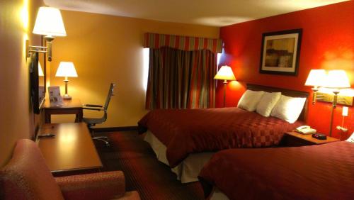 a hotel room with two beds and a desk at Ramada by Wyndham East Orange in East Orange