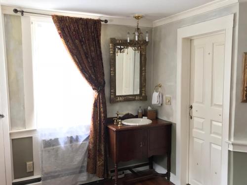 baño con lavabo, espejo y ventana en Admiral Farragut Inn, en Newport