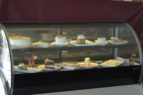 a display case filled with cakes and other desserts at Gazelle International Hotel in Kokopo