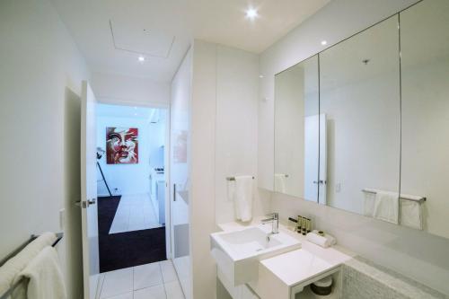 W białej łazience znajduje się umywalka i lustro. w obiekcie The Sebel Melbourne Docklands Hotel w Melbourne