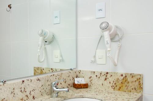 uma casa de banho com um lavatório e 2 secadores de cabelo em Hotel Atlântico em Guarapari