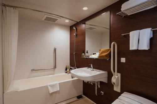 a bathroom with a sink and a toilet and a mirror at Hotel Mystays Premier Akasaka in Tokyo