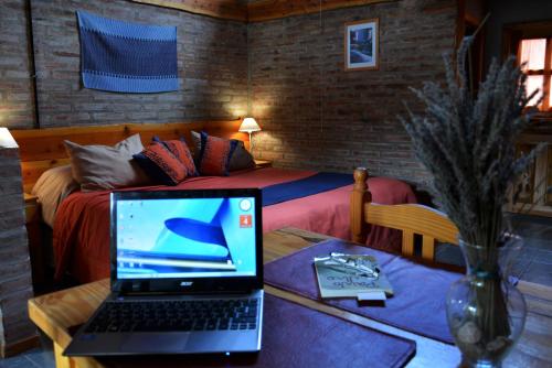 um computador portátil sobre uma mesa num quarto com uma cama em Carpe Diem Cabañas & Suites em El Bolsón