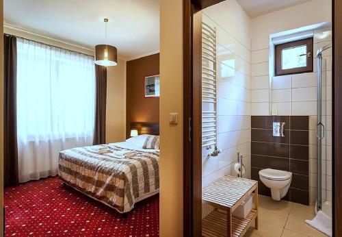 a bedroom with a bed and a bathroom with a shower at Hotel Kochanów in Kochanów