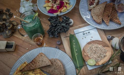 un tavolo in legno ricoperto di piatti di cibo e pane di MaoMeno Yoga Resort a Gili Meno