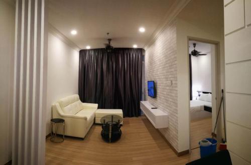 a living room with a white chair and a bed at ExcluSuites Malacca @ The Wave Residence in Melaka