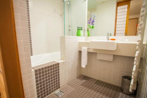 bagno con lavandino, vasca e specchio di Yuki Yama Apartments a Niseko