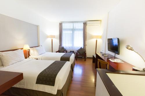 um quarto de hotel com duas camas e uma televisão de ecrã plano em Gumilang Regency Hotel em Bandung