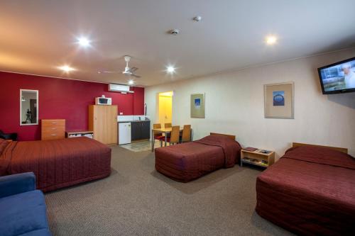 a hotel room with two beds and a flat screen tv at Landmark Manor in New Plymouth