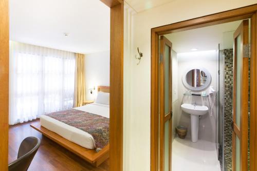 a bedroom with a bed and a sink and a mirror at Gumilang Regency Hotel in Bandung