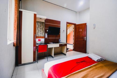 a bedroom with a bed and a desk with a computer at RedDoorz Plus @ Grand City Inn in Makassar