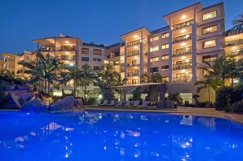 a hotel with a large swimming pool at night at The Mirage Resort Alexandra Headland in Alexandra Headland
