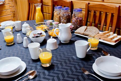a table topped with plates and bowls of food and orange juice at Travellers Retreat B&B in Christchurch