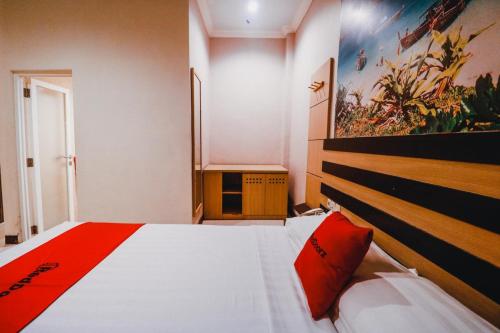 - une chambre avec un grand lit et un oreiller rouge dans l'établissement Reddoorz Plus near Makassar Town Square, à Makassar