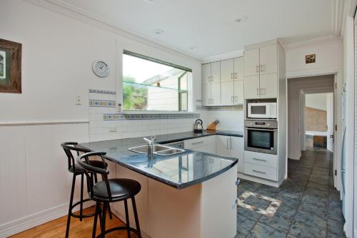 a kitchen with a sink and a counter with two stools at Island Escape with 12m Indoor Pool in Surf Beach