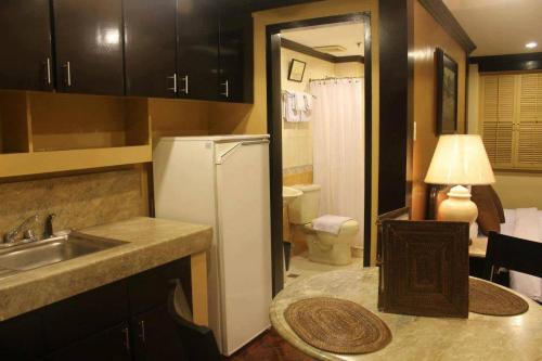 a kitchen with a refrigerator and a sink and a toilet at Lourdes Suites in Manila