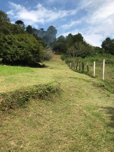 a grassy field with a fence and trees at Cabaña Mountain View in Heredia