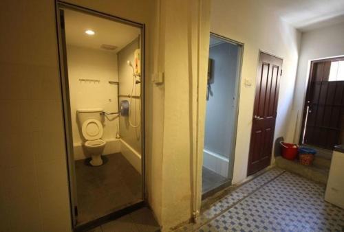 a bathroom with a toilet and a glass door at Cocoa Mews Cafe and Homestay in George Town