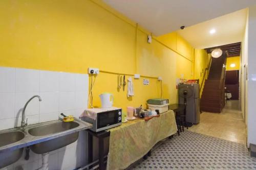 a kitchen with a sink and a microwave at Cocoa Mews Cafe and Homestay in George Town