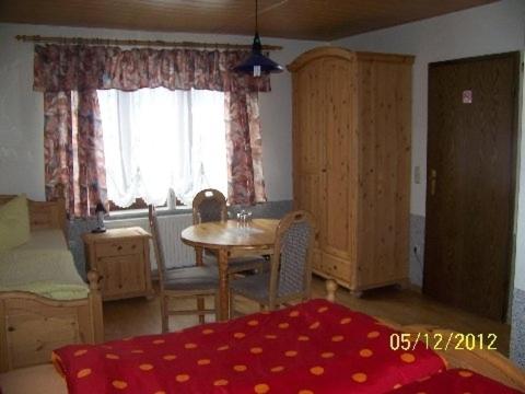 Zimmer mit einem Tisch, Stühlen und einem Fenster in der Unterkunft Pension Strohbach in Sebnitz