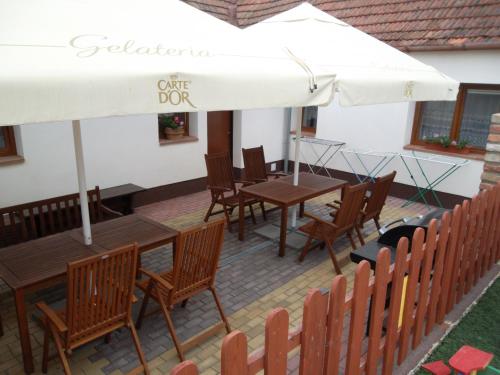 un patio con mesas, sillas y una sombrilla blanca en Ubytování u Maminky en Lednice