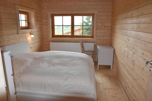 Schlafzimmer mit einem Bett, einem Tisch und einem Fenster in der Unterkunft Erzgebirgsholzhaus am Lugstein in Kurort Altenberg