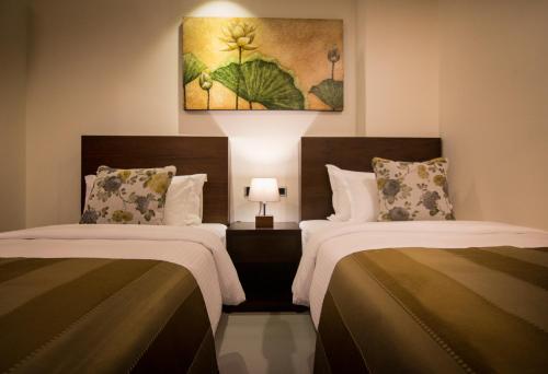 ein Hotelzimmer mit 2 Betten und einem Gemälde an der Wand in der Unterkunft Rococo Residence in Colombo