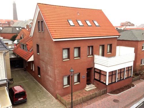 une grande maison en briques rouges avec un toit orange dans l'établissement BORKUMUNTERKUNFT - WOH3 - IM HERZEN DER INSEL, à Borkum