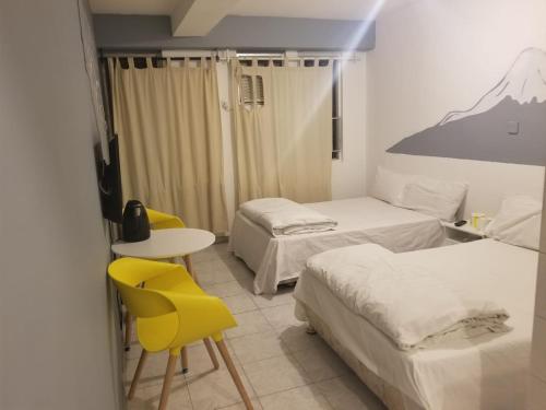 Habitación con 2 camas, mesa y sillas amarillas. en Silverview Resort Holiday, en Hong Kong