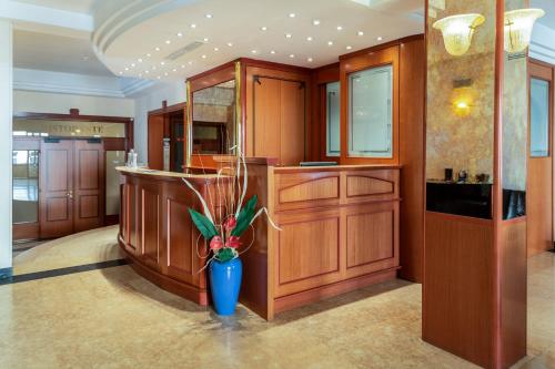 a kitchen with wooden cabinets and a blue vase with a plant at Hotel Nettunia in Rimini