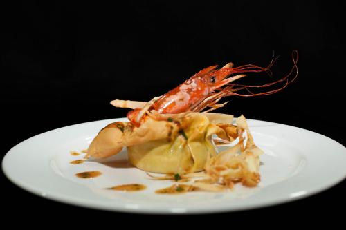 a shrimp on a white plate on a black background at Albergo Ristorante Madonnina in Cantello