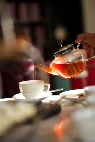 uma pessoa a deitar chá numa chávena sobre uma mesa em Outrigger Mauritius Beach Resort em Bel Ombre