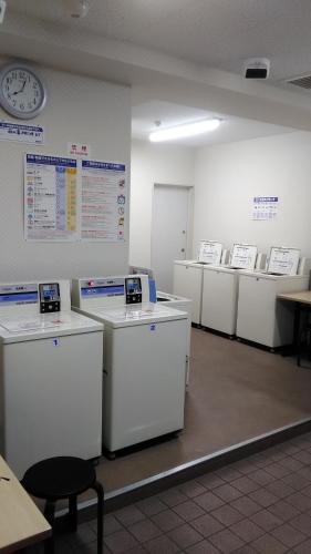 a room with a row of refrigerators and a clock at Base Inn Uguisudani in Tokyo