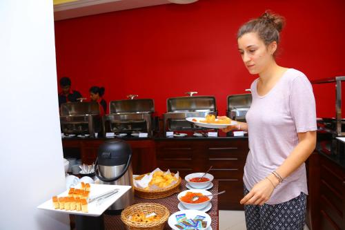a woman standing in a kitchen holding a plate of food at Hotel Nippon Colombo in Colombo