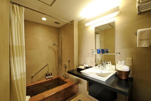 a bathroom with a sink and a shower and a tub at Akakura Kanko Hotel in Myoko
