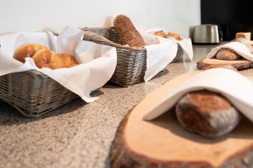 a table topped with baskets of bread and pastries at Mercure Chur City West in Chur
