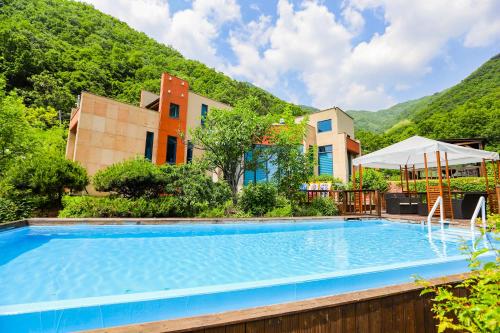 a pool at a resort with mountains in the background at Penatess Pool Villa in Chungju