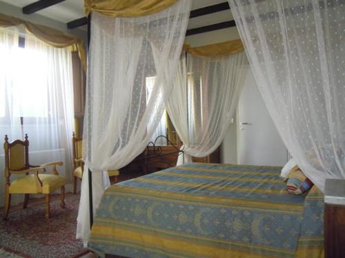 1 dormitorio con 1 cama con cortinas y silla en agriturismo Piccolo Albero, en Loreto Aprutino