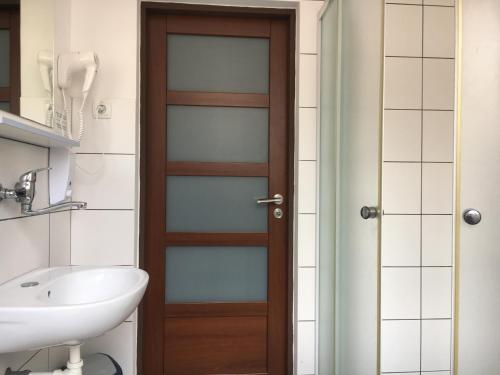 a bathroom with a wooden door and a sink at Pension Village in Karlovy Vary