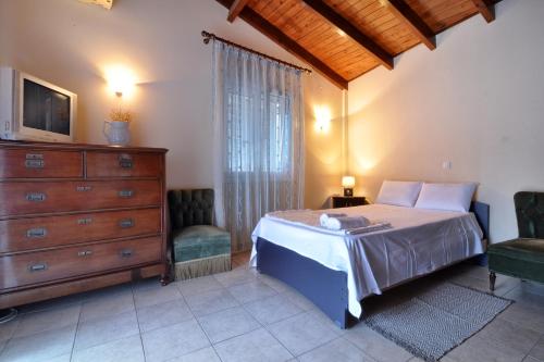 een slaapkamer met een bed, een dressoir en een tv bij Angelica's House in Mantoúkion